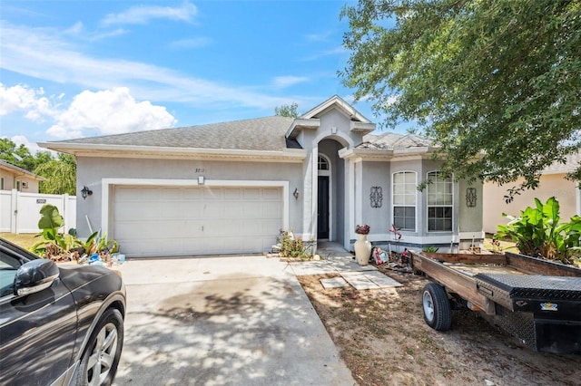 ranch-style house featuring fence, a shingled roof, a garage, stucco siding, and concrete driveway