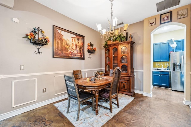 dining room featuring arched walkways, concrete flooring, a notable chandelier, and visible vents