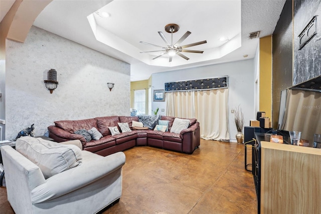 living area featuring visible vents, concrete flooring, a raised ceiling, a ceiling fan, and a skylight