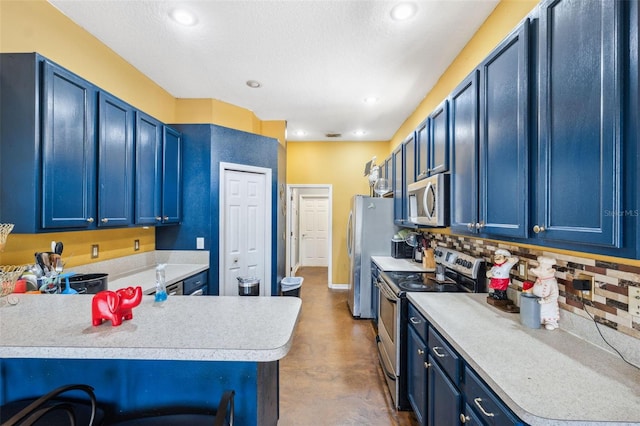 kitchen with decorative backsplash, a peninsula, light countertops, blue cabinets, and stainless steel appliances