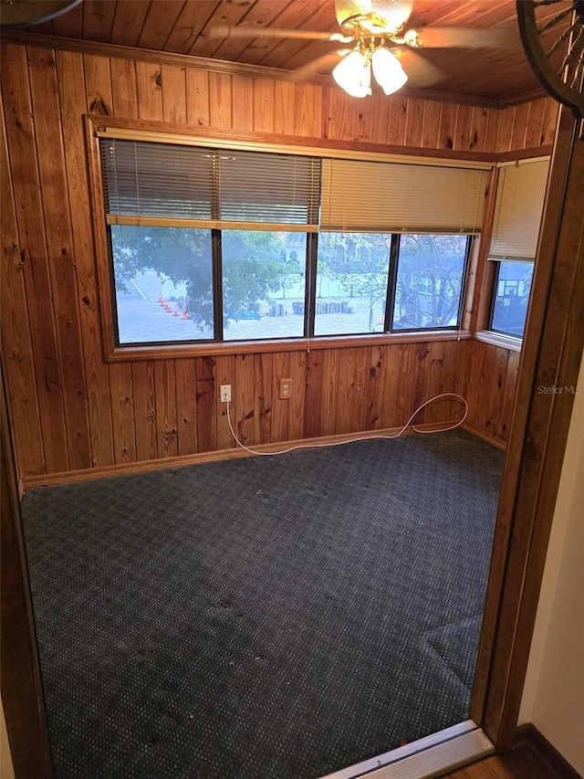 spare room with baseboards, wood ceiling, ceiling fan, and wooden walls