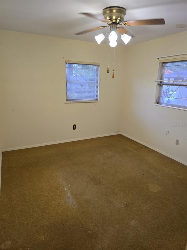 carpeted empty room featuring a ceiling fan and baseboards