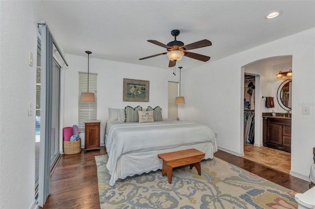 bedroom featuring wood finished floors, arched walkways, recessed lighting, ceiling fan, and ensuite bath