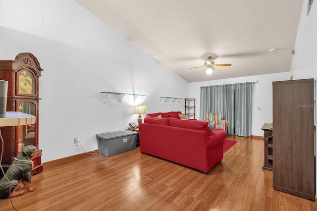 living area with ceiling fan, wood finished floors, and vaulted ceiling