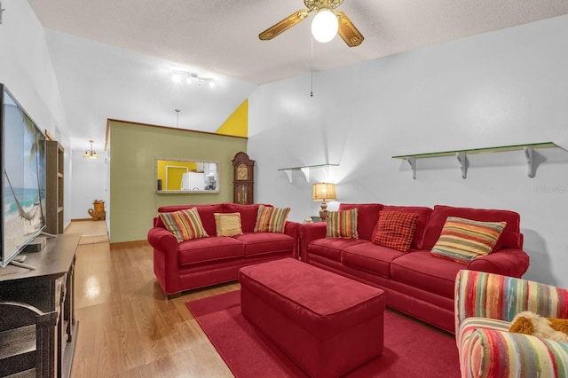 living area with a ceiling fan, a textured ceiling, wood finished floors, and lofted ceiling