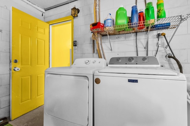 clothes washing area with concrete block wall, laundry area, and washer and clothes dryer
