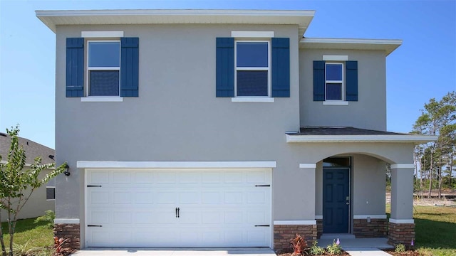 traditional-style home featuring concrete driveway, a garage, and stucco siding