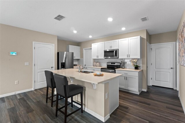 kitchen featuring appliances with stainless steel finishes, a sink, baseboards, visible vents, and dark wood-style floors