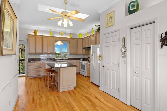 kitchen featuring a breakfast bar area, a ceiling fan, a skylight, ornamental molding, and white appliances