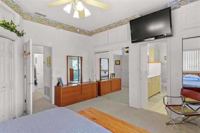 bedroom with light colored carpet, a ceiling fan, ensuite bath, and visible vents