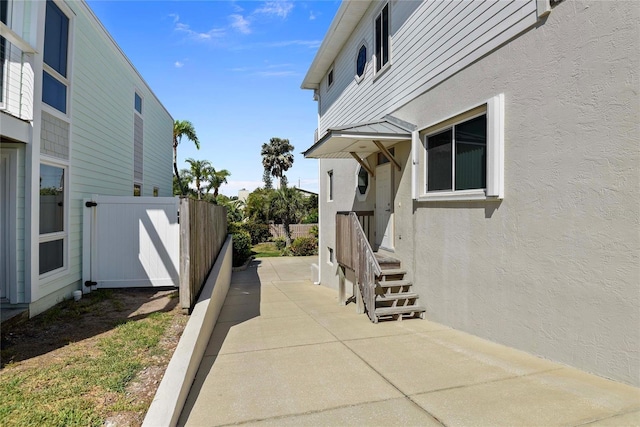 view of side of property with fence, a patio, stucco siding, and entry steps