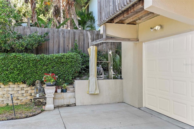 view of patio featuring fence and a garage