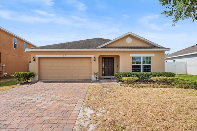 3345 Reedy Glen Dr, Kissimmee, FL 34758 - ranch-style house featuring decorative driveway, an attached garage, fence, and stucco siding