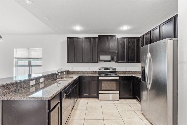 3345 Reedy Glen Dr, Kissimmee, FL 34758 - kitchen with a peninsula, a sink, dark stone countertops, light tile patterned floors, and black appliances