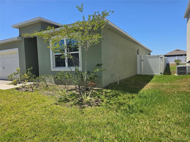view of home's exterior featuring central AC unit, a garage, fence, a yard, and stucco siding