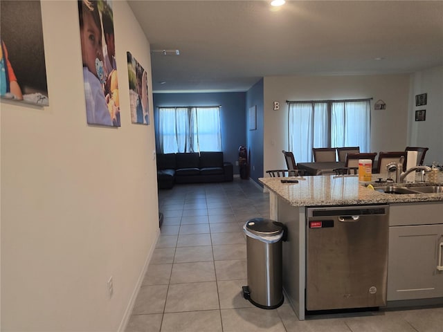 kitchen featuring a sink, light tile patterned floors, baseboards, and dishwasher