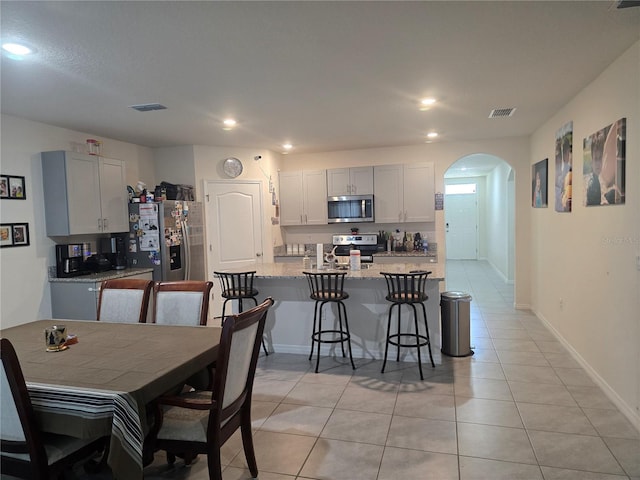 dining room with visible vents, arched walkways, light tile patterned floors, and recessed lighting