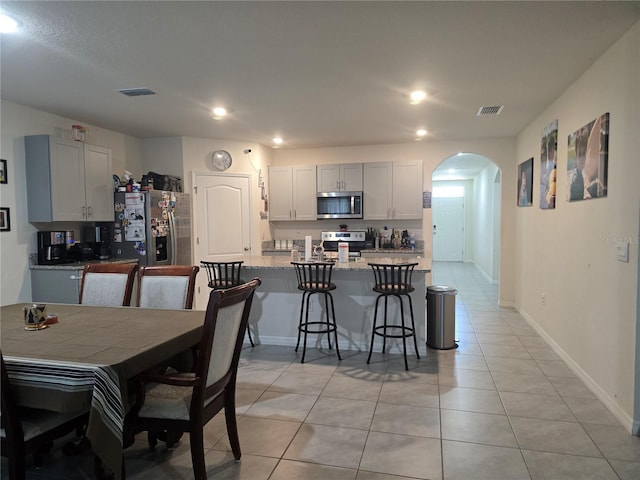 dining area with light tile patterned floors, arched walkways, recessed lighting, and visible vents