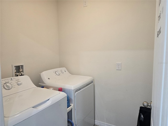 clothes washing area with baseboards, laundry area, and washing machine and clothes dryer