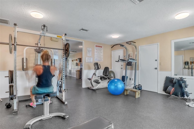 136 Beach Park Ln Unit 35, Cape Canaveral, FL 32920 - workout area with a textured ceiling and a wainscoted wall