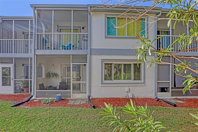 136 Beach Park Ln Unit 35, Cape Canaveral, FL 32920 - rear view of house with stucco siding, a sunroom, and a yard