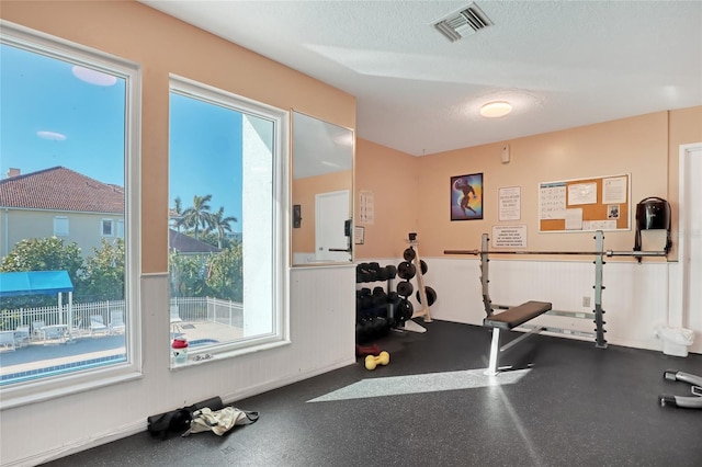 136 Beach Park Ln Unit 35, Cape Canaveral, FL 32920 - workout room with a textured ceiling and wainscoting