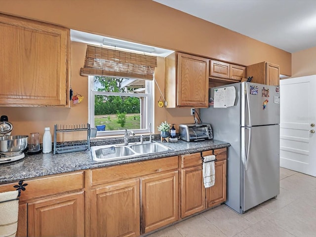 16 E Orange St, Davenport, FL 33837 - kitchen with dark countertops, a sink, a toaster, freestanding refrigerator, and light tile patterned flooring