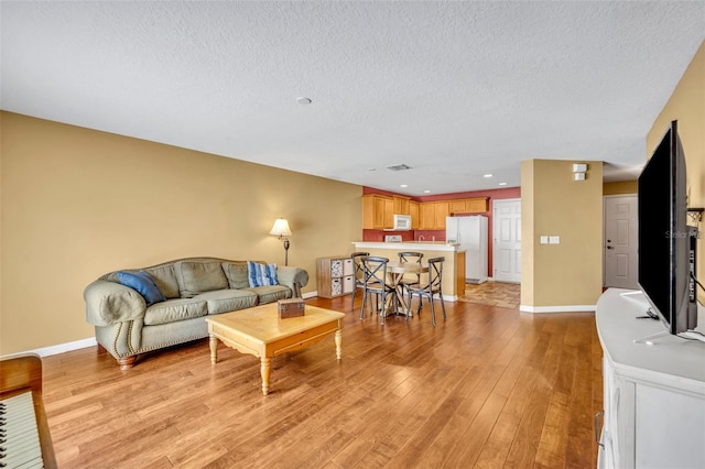 5102 Monticello Heights Ln, Oviedo, FL 32765 - living room featuring a textured ceiling, light wood-type flooring, baseboards, and recessed lighting
