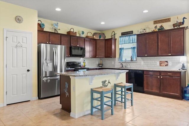 kitchen featuring a center island, decorative backsplash, a breakfast bar, and black appliances