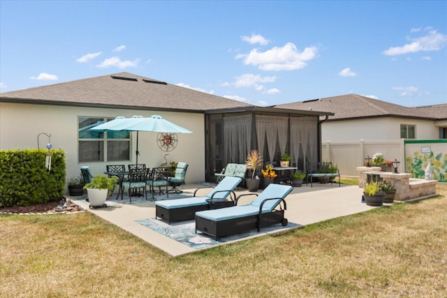 rear view of house with a patio, a lawn, fence, and stucco siding