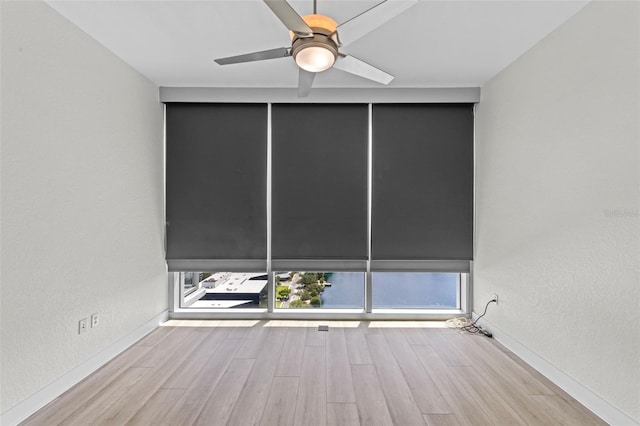 spare room with baseboards, ceiling fan, a textured wall, and wood finished floors