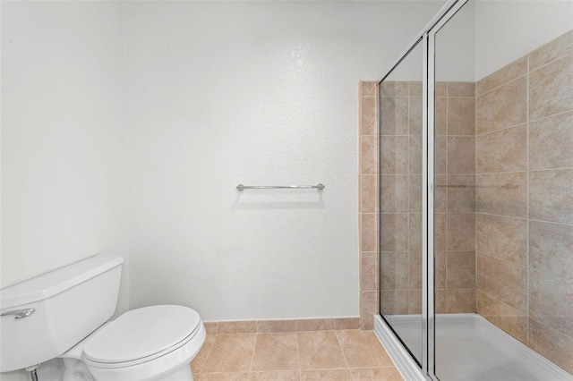 full bathroom featuring baseboards, tile patterned floors, a stall shower, and toilet