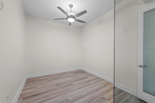 spare room featuring a textured ceiling, baseboards, a ceiling fan, and light wood-style flooring