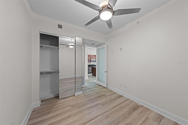 unfurnished bedroom featuring baseboards, a closet, light wood-style flooring, and visible vents