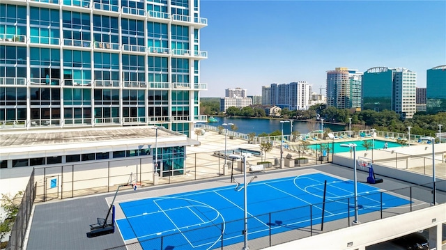 exterior space with fence, community basketball court, a water view, and a view of city
