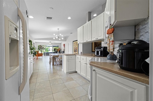 11908 Delfina Ln, Orlando, FL 32827 - kitchen featuring a peninsula, light tile patterned floors, white cabinets, visible vents, and vaulted ceiling