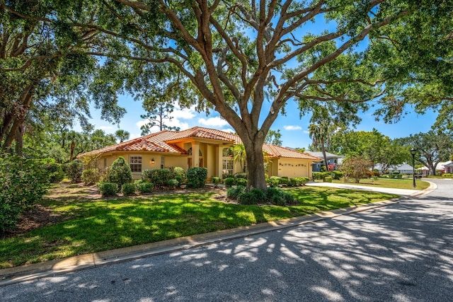 8202 Shadow Pine Way, Sarasota, FL 34238 - mediterranean / spanish-style house with a garage, concrete driveway, a tiled roof, stucco siding, and a front yard