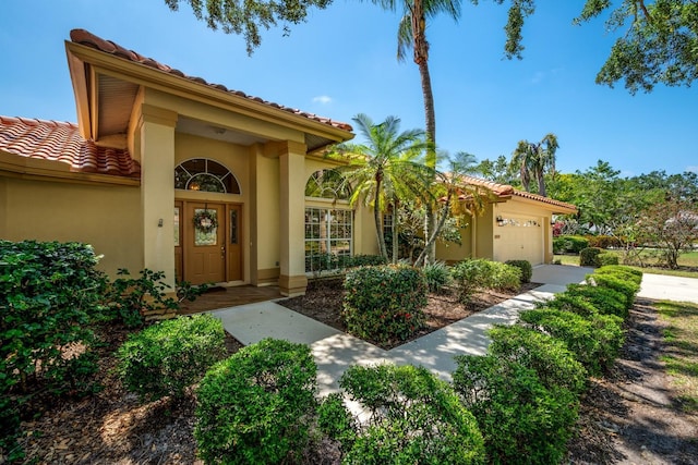 8202 Shadow Pine Way, Sarasota, FL 34238 - view of exterior entry with a garage, a tiled roof, stucco siding, and driveway