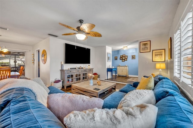 living area with visible vents, a ceiling fan, baseboards, and wood finished floors
