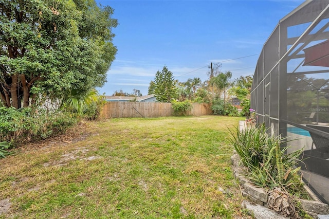 view of yard featuring glass enclosure and a fenced backyard