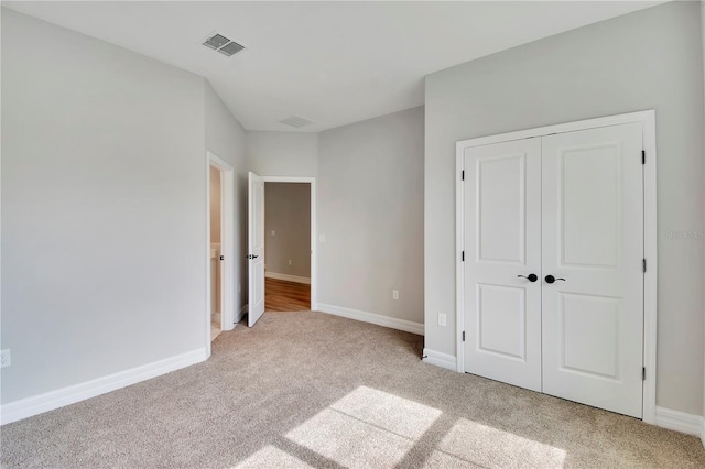 unfurnished bedroom with baseboards, visible vents, light carpet, and a closet
