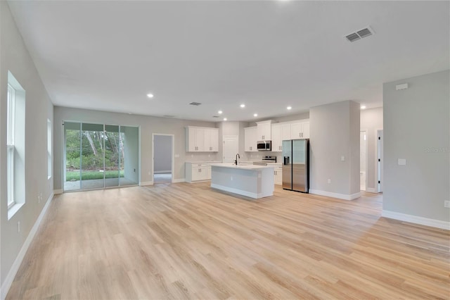 kitchen featuring baseboards, visible vents, stainless steel appliances, and open floor plan