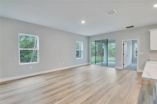 unfurnished living room featuring baseboards, visible vents, and light wood-type flooring