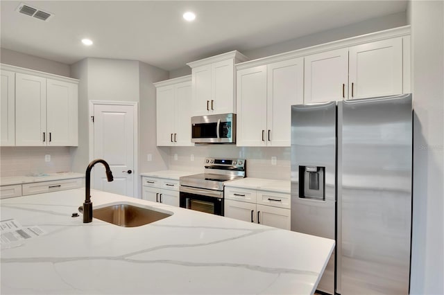 kitchen featuring backsplash, a sink, white cabinets, stainless steel appliances, and recessed lighting
