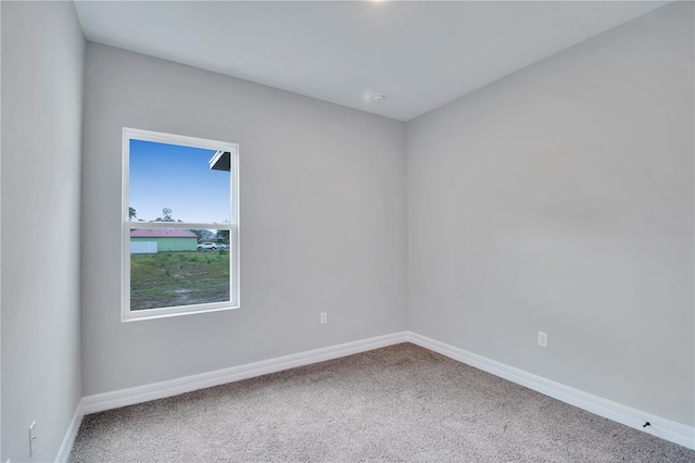 spare room featuring carpet floors and baseboards