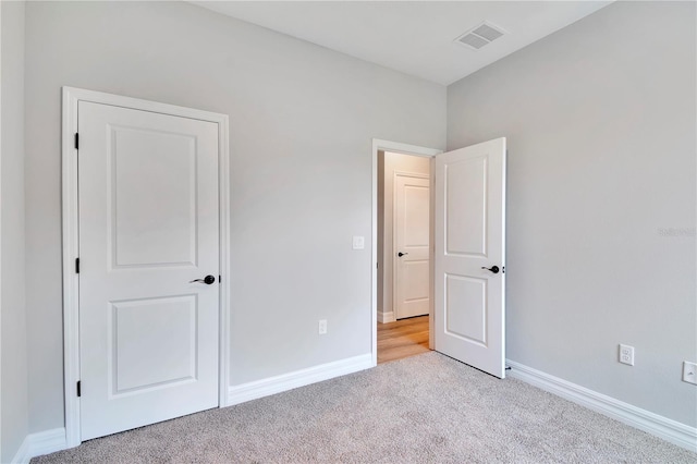 unfurnished bedroom with baseboards, visible vents, and light colored carpet