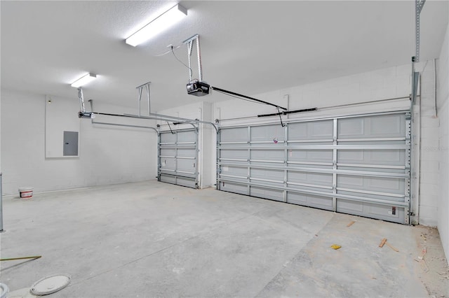 garage featuring concrete block wall, a garage door opener, and electric panel