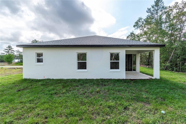rear view of property with a patio, a lawn, and stucco siding