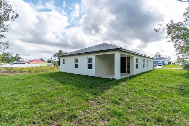 back of property with a patio, a lawn, and stucco siding