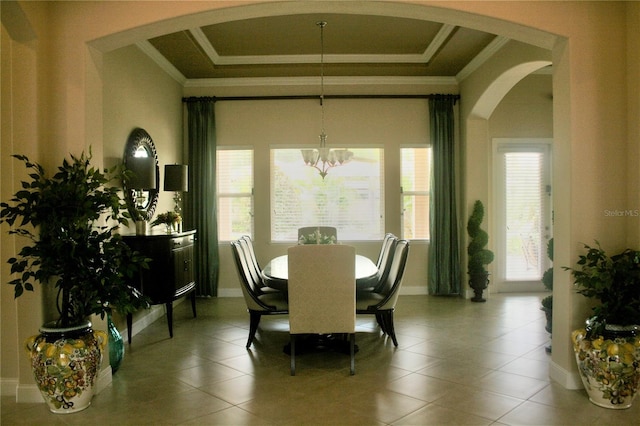 tiled dining space with crown molding, baseboards, a tray ceiling, arched walkways, and a notable chandelier